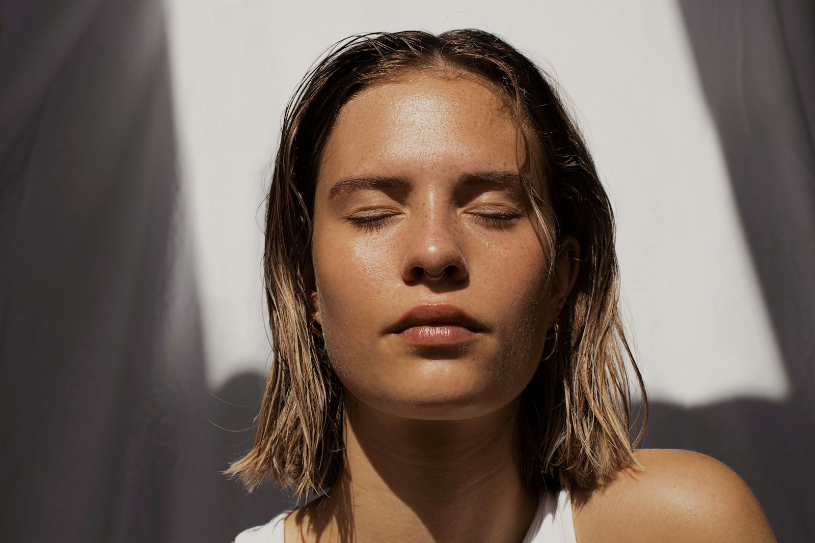 Woman with natural, bare skin and eyes closed in soft daylight